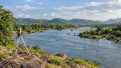 A broad river flowing through a green Deccan landscape, low hills and a modest survey tripod on near bank. No dam or completed project shown; conceptual river water planning.